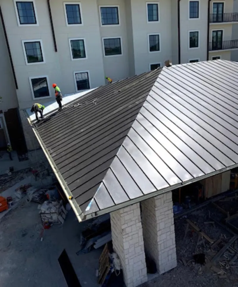 Crew installing standing seam metal roof panels on a commercial project in Nolensville